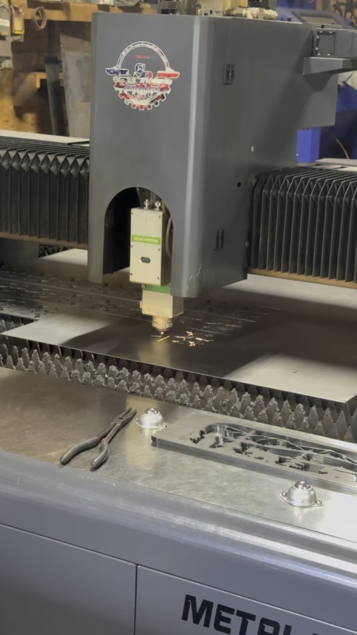 Fiber laser cutting head over a steel sheet, sparks at the cut